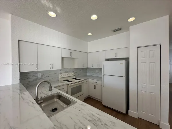 a kitchen with stainless steel appliances granite countertop a refrigerator a sink a stove and a refrigerator
