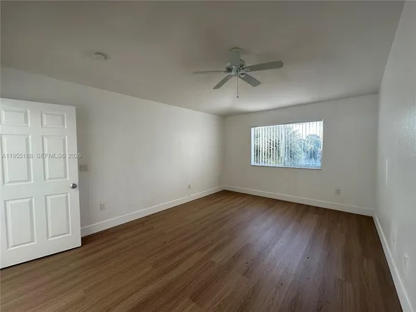 a view of an empty room with wooden floor and a window
