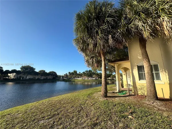 a view of a house with lake view and a trees in the background