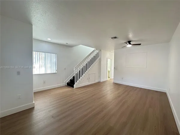 a view of an empty room with wooden floor and a window