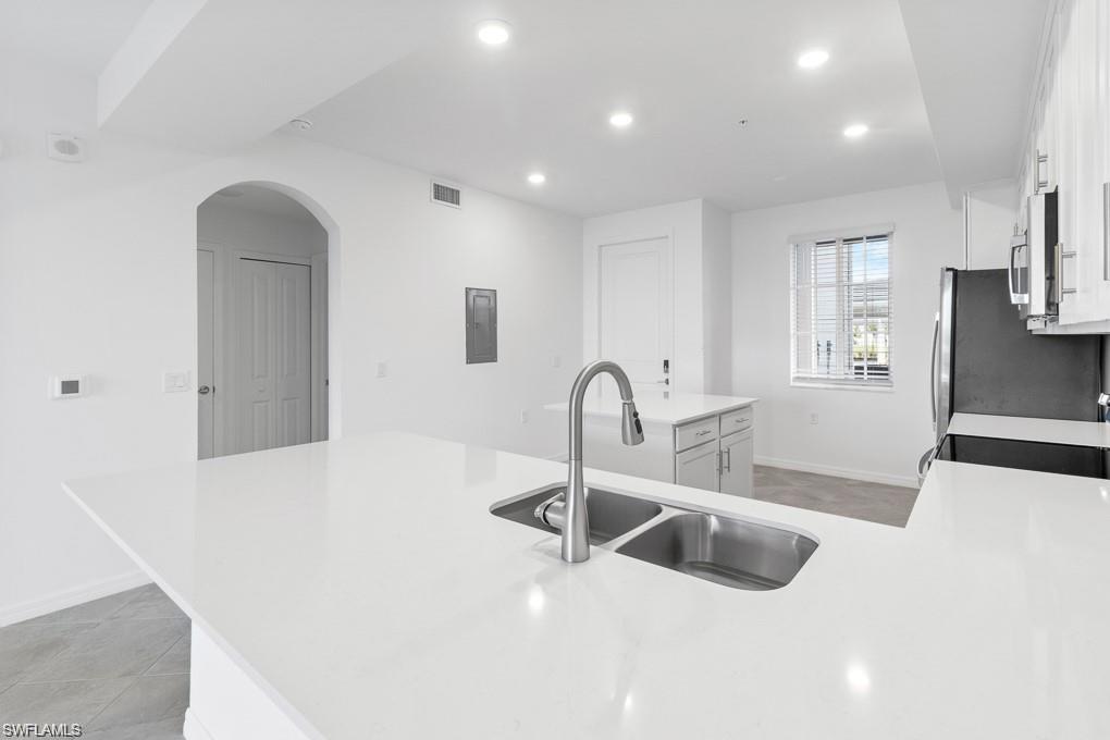 5651 Double Eagle Circle, Unit 4314 Immokalee, FL 34142 - Photo 4 of 41 Kitchen with a peninsula, arched walkways, white cabinetry, recessed lighting, and light stone countertops