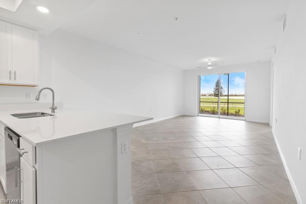 5651 Double Eagle Circle, Unit 4314 Immokalee, FL 34142 - Photo 41 of 41 Kitchen featuring white cabinetry, light tile patterned floors, stainless steel dishwasher, open floor plan, and light stone counters