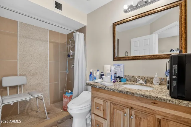 a bathroom with a granite countertop sink mirror vanity and toilet