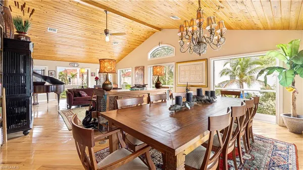 a dining room with wooden floor a chandelier a wooden table and chairs