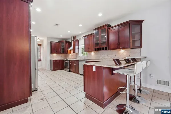 a kitchen with stainless steel appliances granite countertop a stove top oven a sink and a refrigerator