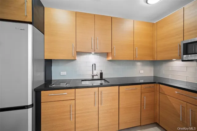 a kitchen with stainless steel appliances granite countertop a sink a refrigerator and a cabinets