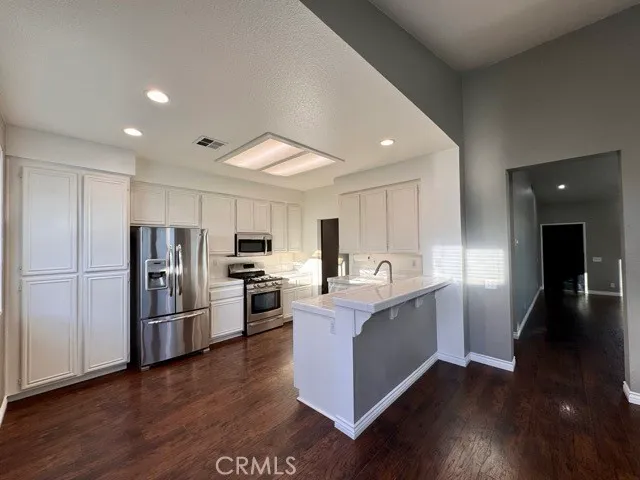 a large kitchen with a center island wooden floor and stainless steel appliances