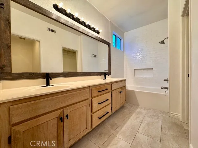 a spacious bathroom with a double vanity sink a mirror and a bathtub
