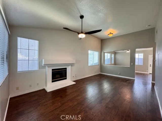 a view of wooden floor fire place and windows in an empty room