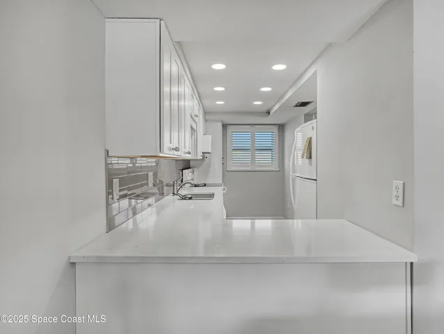 a large white kitchen with sink and window