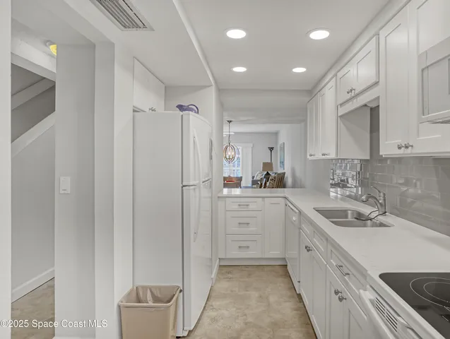 a kitchen with white cabinets and sink