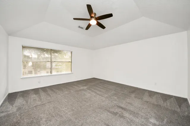 an empty room with a ceiling fan and window