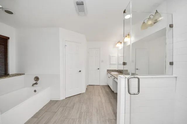 a bathroom with a granite countertop sink a mirror and a bathtub