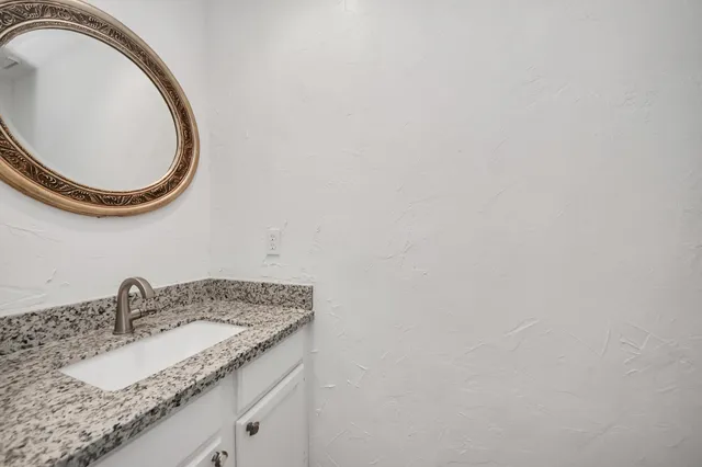 a bathroom with a granite countertop sink and a mirror