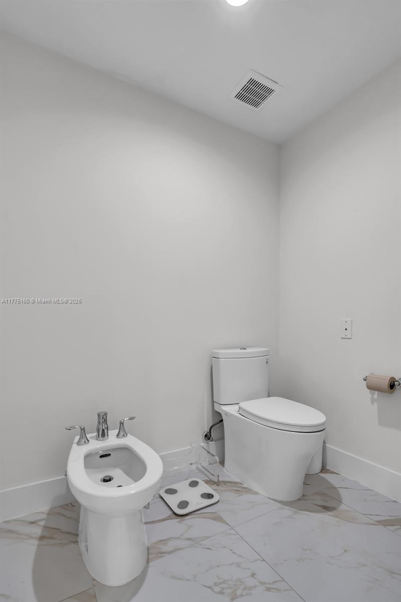 765 Crandon Boulevard, Unit 202 Key Biscayne, FL 33149 - Photo 15 of 41 a white toilet sitting next to a bathroom sink and vanity