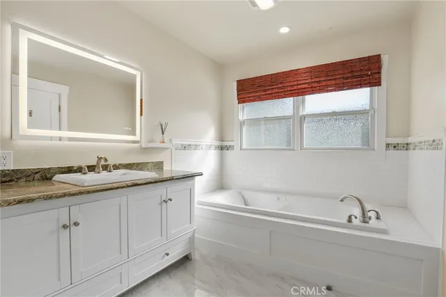 a bathroom with a granite countertop sink mirror and bathtub