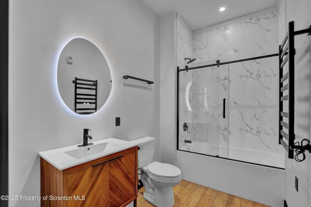 a view of an empty room with wooden floor and a ceiling fan