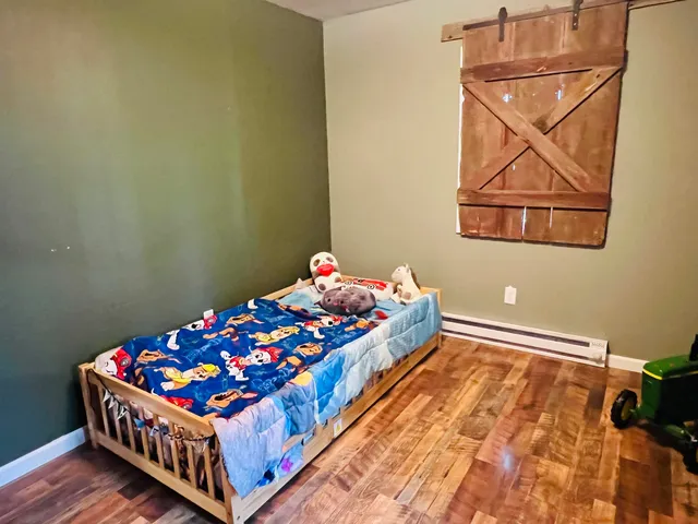 a bedroom with a bed and wooden floor