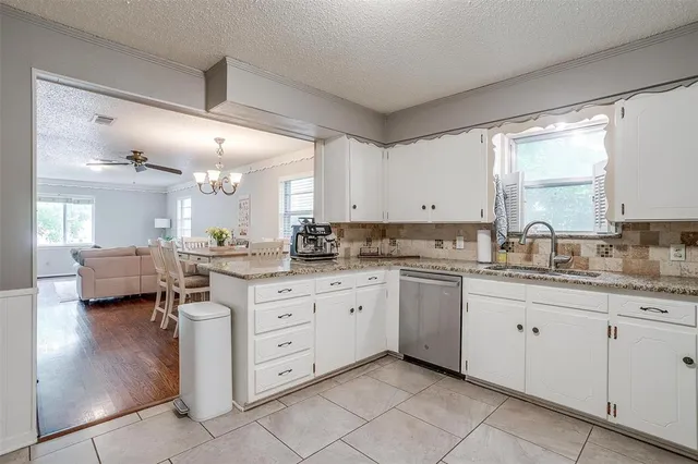 a kitchen with granite countertop white cabinets stainless steel appliances and a counter space