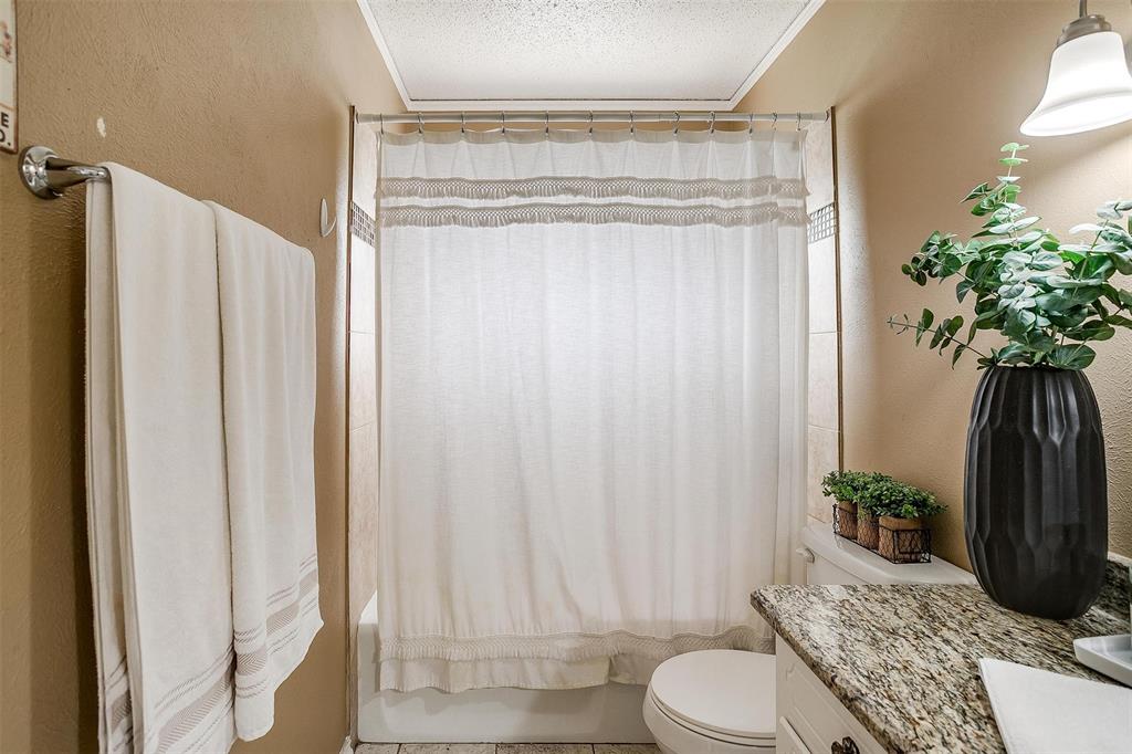 3217 Lubbock Avenue Fort Worth, TX 76109 - Photo 21 of 38 a bathroom with a shower curtain a mirror and a toilet