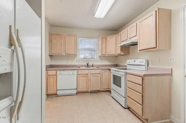 a kitchen with white cabinets stainless steel appliances and a window