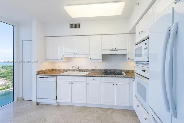 a kitchen with granite countertop a refrigerator sink and cabinets