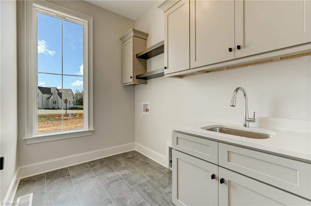 7688 Kyran Court Oak Ridge, NC 27310 - Photo 23 of 36 Main level laundry room with sink and additional storage