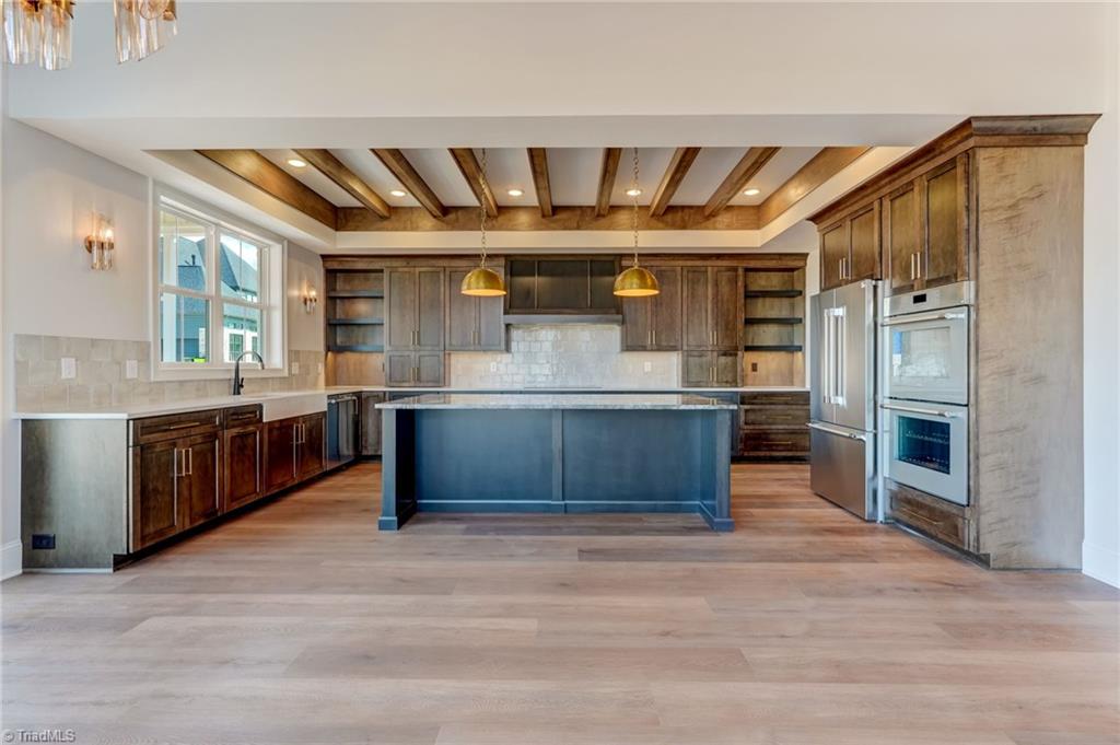 7688 Kyran Court Oak Ridge, NC 27310 - Photo 3 of 36 Custom chef's kitchen featuring large island with quartzite countertop, Thermador appliances, induction cooktop, walk in pantry, ample cabinetry