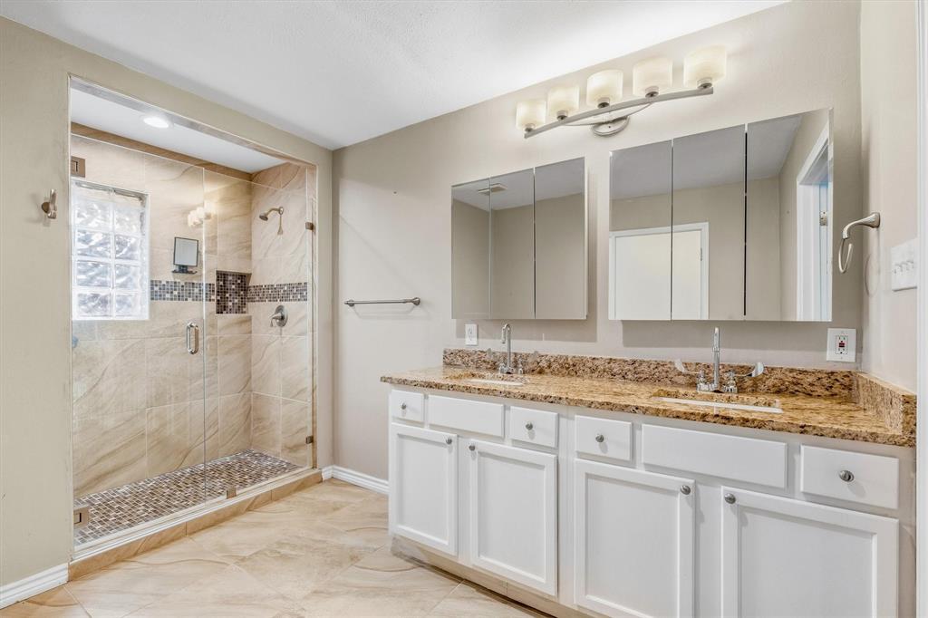 4436 Thunder Road Dallas, TX 75244 - Photo 24 of 33 Dual vanity with granite countertops, tile flooring, glass-enclosed shower, mosaic tile accents, and recessed shower lighting