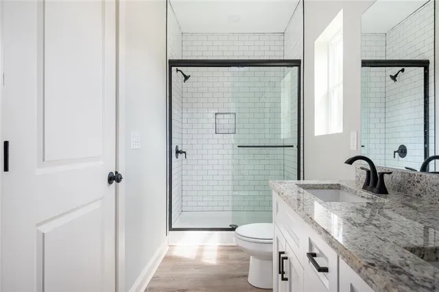 a bathroom with a granite countertop sink toilet and shower