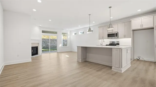 a kitchen with stainless steel appliances kitchen island wooden cabinets a stove a sink and a wooden floor