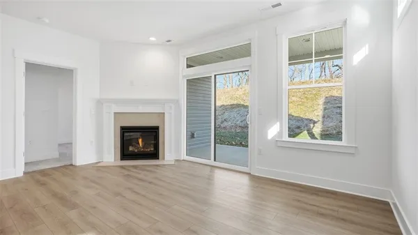 an empty room with wooden floor a fireplace and windows