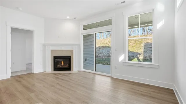 an empty room with wooden floor a fireplace and windows