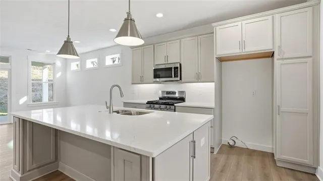 a kitchen with stainless steel appliances a sink a stove a refrigerator cabinets and a dining table