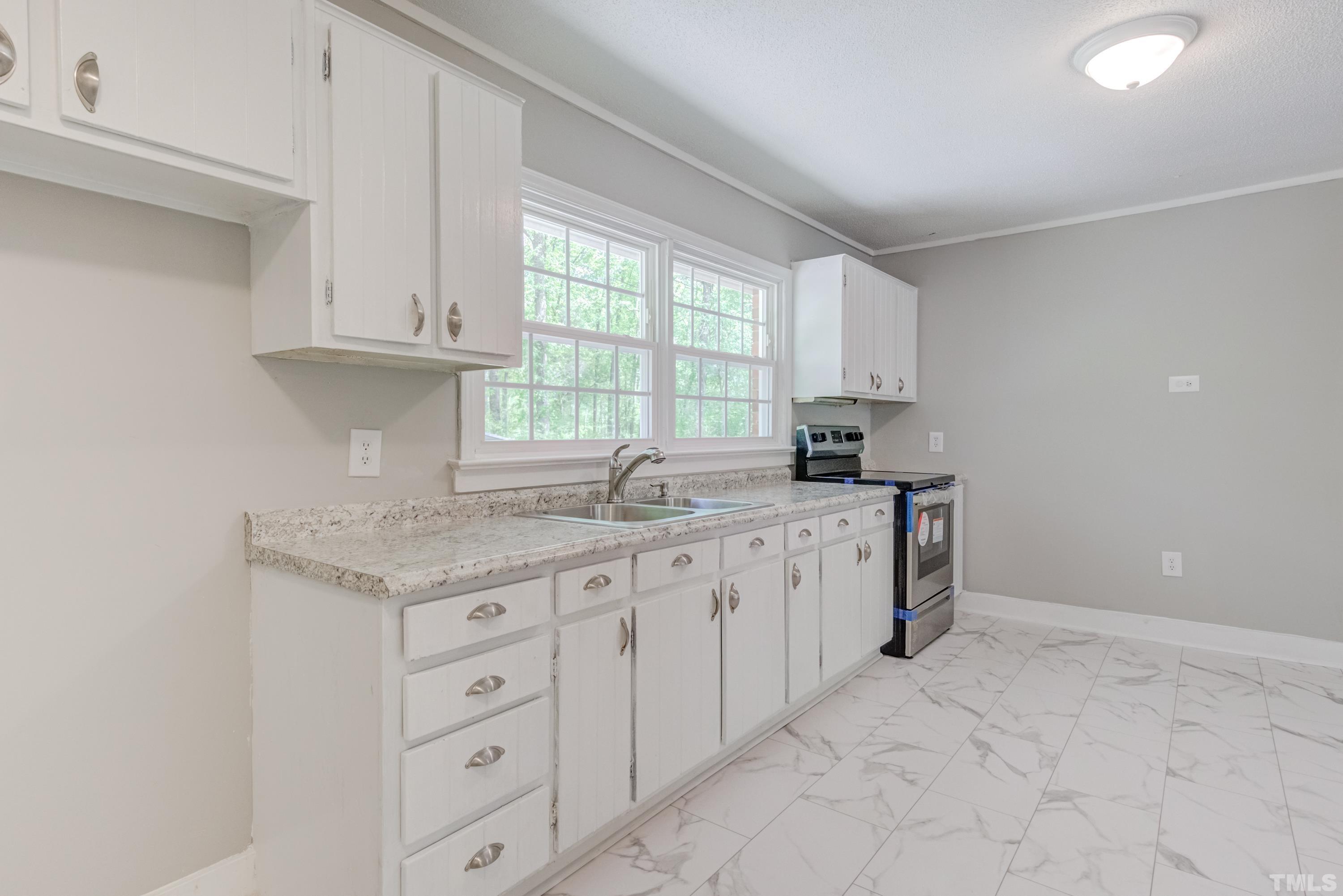 6005 Meadowbrook Road Raleigh, NC 27603 - Photo 12 of 42 a kitchen with granite countertop white cabinets white appliances a sink and a window