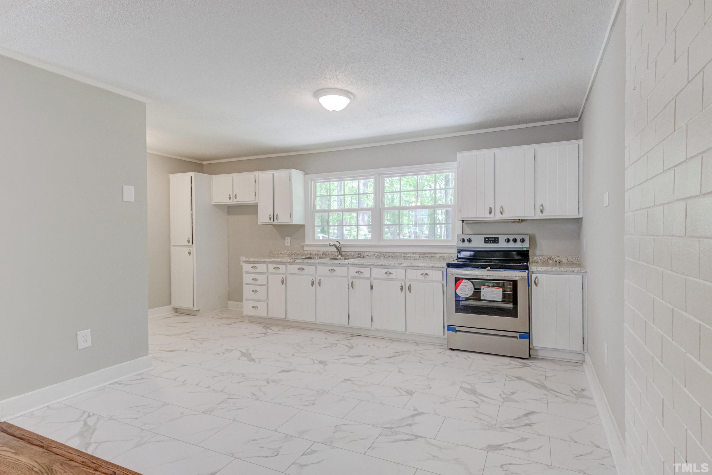 6005 Meadowbrook Road Raleigh, NC 27603 - Photo 8 of 42 a kitchen with white cabinets and appliances