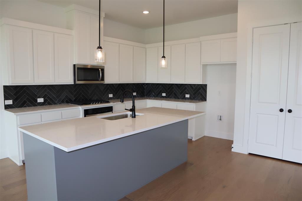 205 Chestnut Celina, TX 75009 - Photo 6 of 19 a kitchen with stainless steel appliances a sink a stove a refrigerator a white center island and cabinets