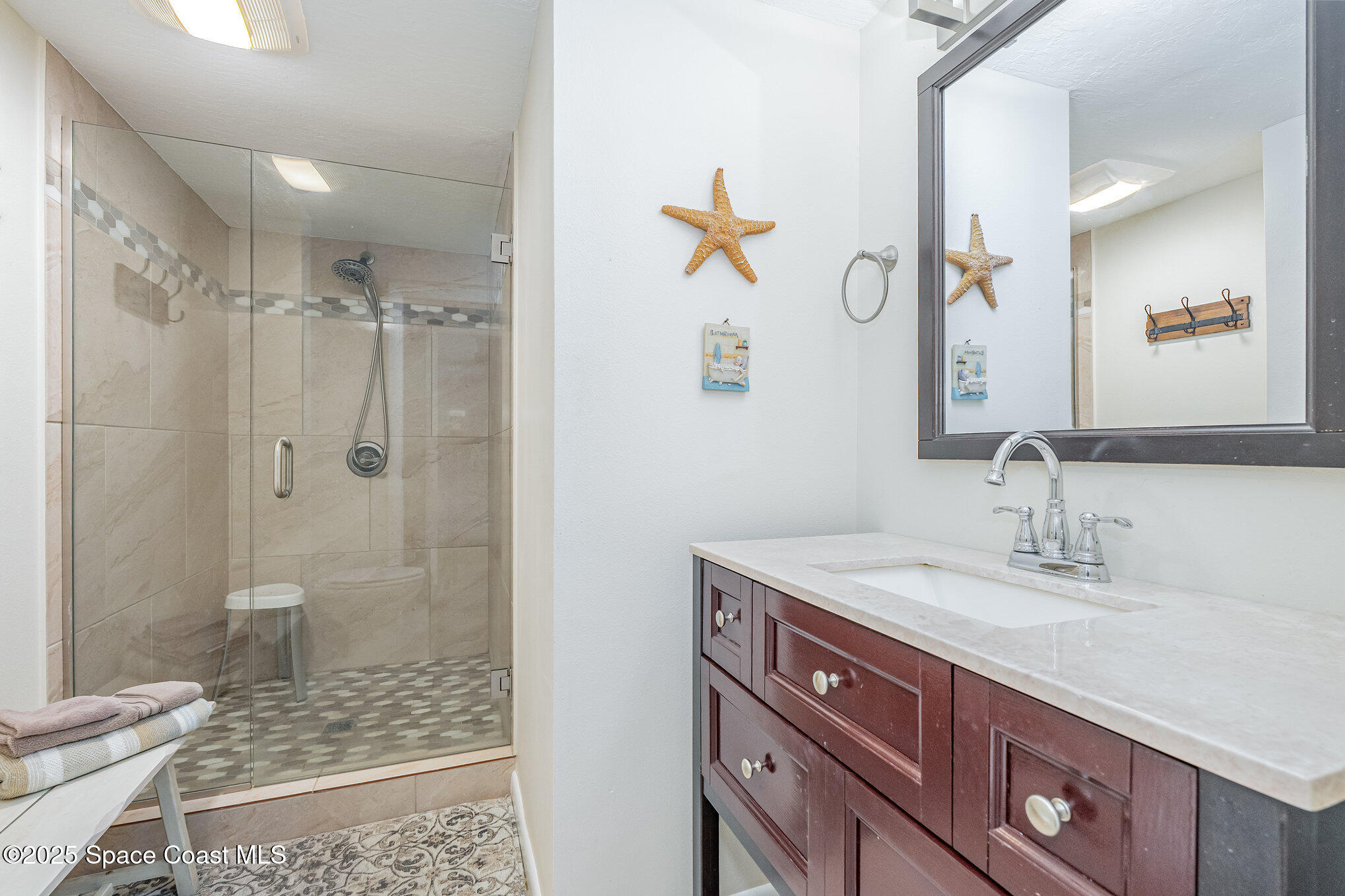 5000 Ocean Beach Boulevard, Unit C5 Cocoa Beach, FL 32931 - Photo 17 of 31 a bathroom with a granite countertop sink a mirror a glass door and shower