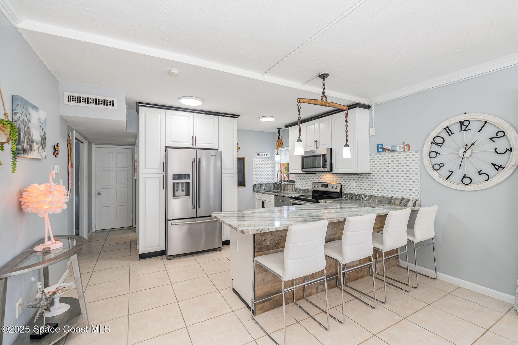 5000 Ocean Beach Boulevard, Unit C5 Cocoa Beach, FL 32931 - Photo 4 of 31 a kitchen with stainless steel appliances kitchen island granite countertop a refrigerator and a stove top oven