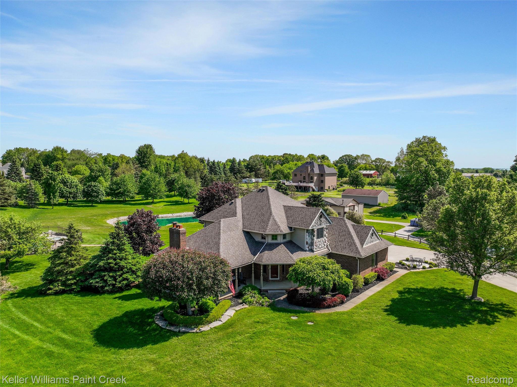 5813 36 Mile Road Romeo, MI 48065 - Photo 50 of 81 Expansive property featuring a stone and siding exterior, multi-gabled roofline, mature trees, manicured lawns, and a private swimming pool