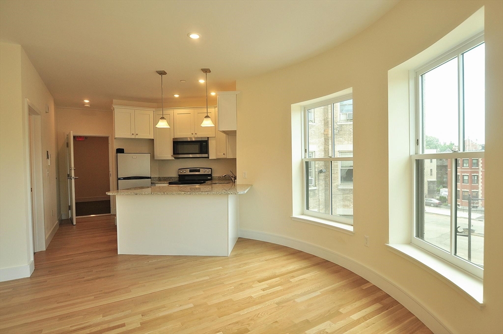 a view of open kitchen with white cabinets and wooden floor
