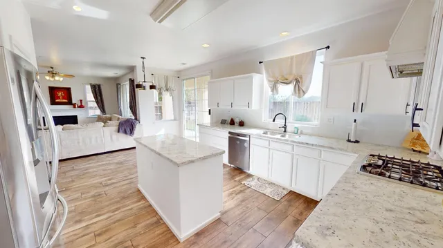 a large white open kitchen with stainless steel appliances kitchen island granite countertop a sink and cabinets