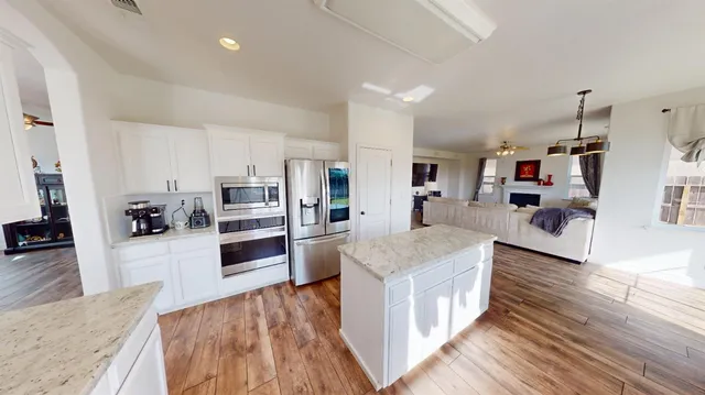 a large kitchen with stainless steel appliances wooden floors and wooden cabinets