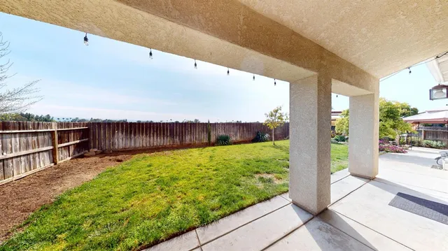 a view of a house with brick walls and a yard with a large tree front of it