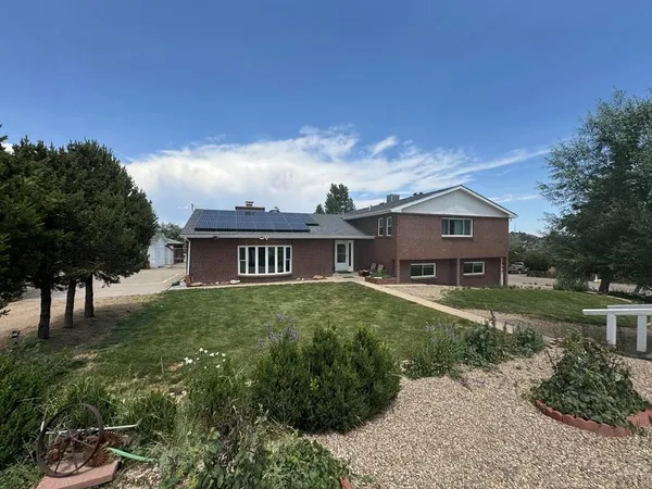 a view of a house with a big yard plants and large trees
