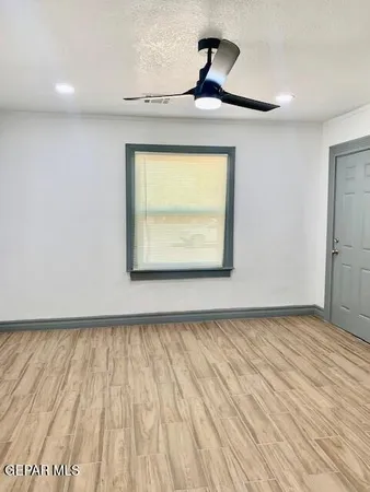 a view of empty room with wooden floor and fan