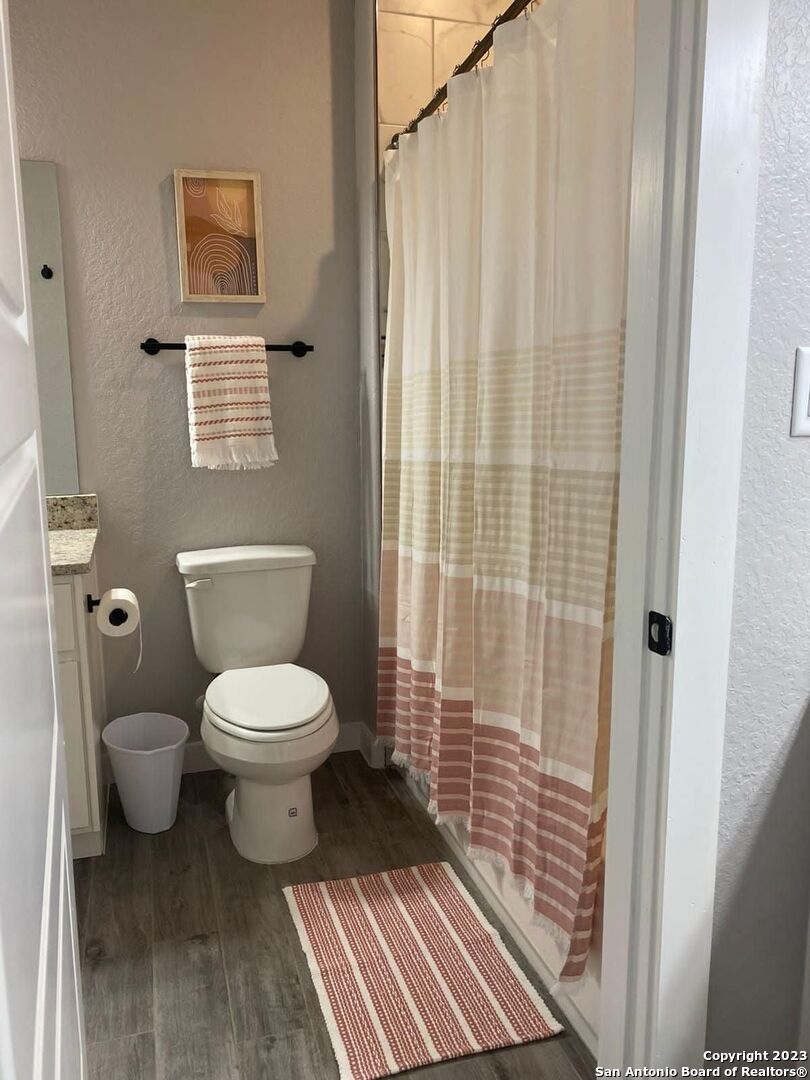 6160 Eckhert Road, Unit 1406 San Antonio, TX 78240 - Photo 13 of 14 a bathroom with a toilet and a shower curtain