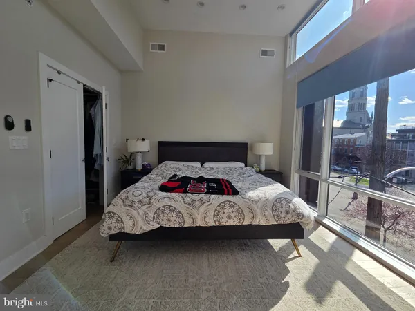 a bedroom with a bed and large windows