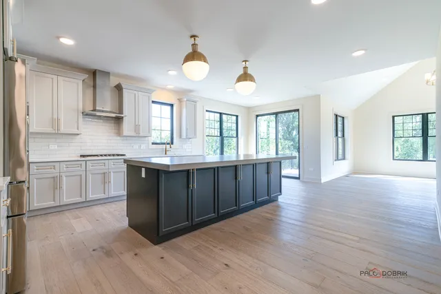 a kitchen with stainless steel appliances granite countertop a sink cabinets and wooden floor