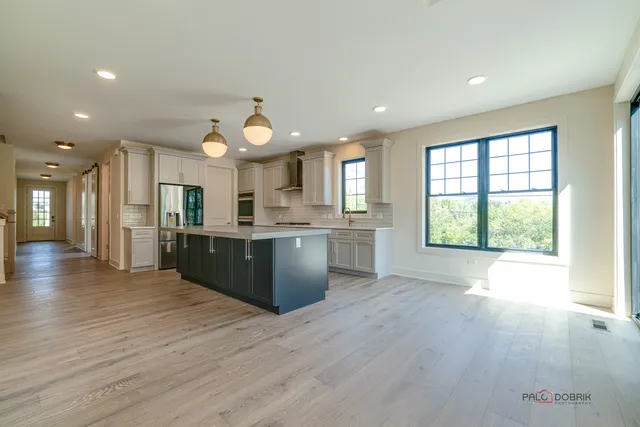 a large kitchen with a large counter top a sink stainless steel appliances and cabinets